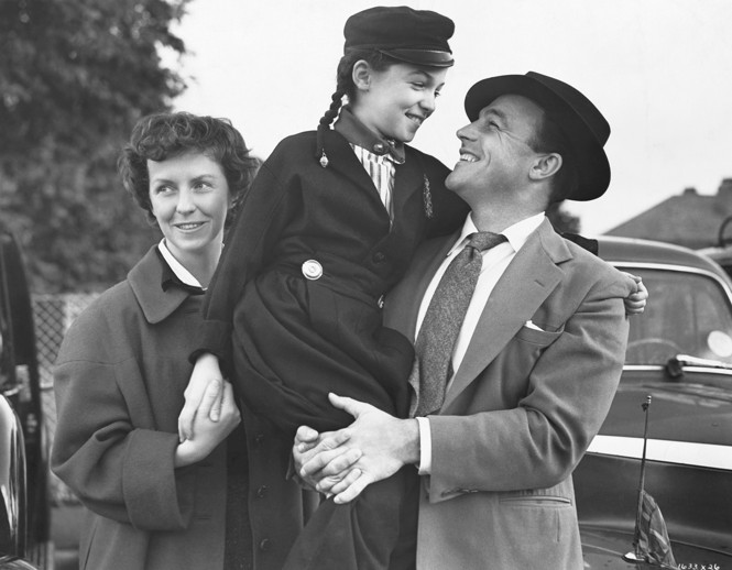 A black and white photograph of Gene Kelly with his wife and daughter