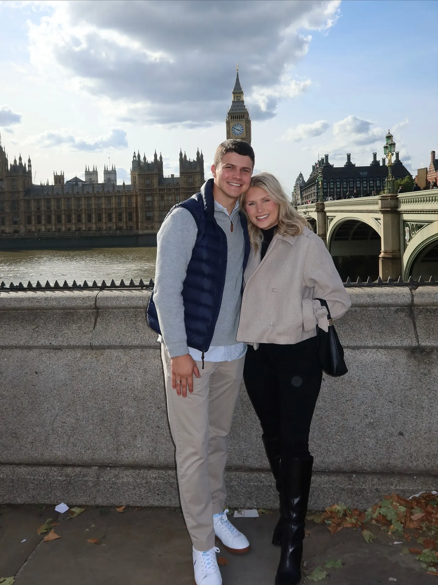 Katie Bates and Travis Clark smiling in front of Big Ben and the Houses of Parliament in London.