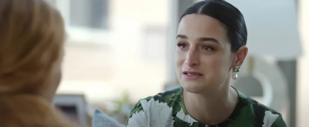 Jenny Slate crying while wearing a green and white patterned top.