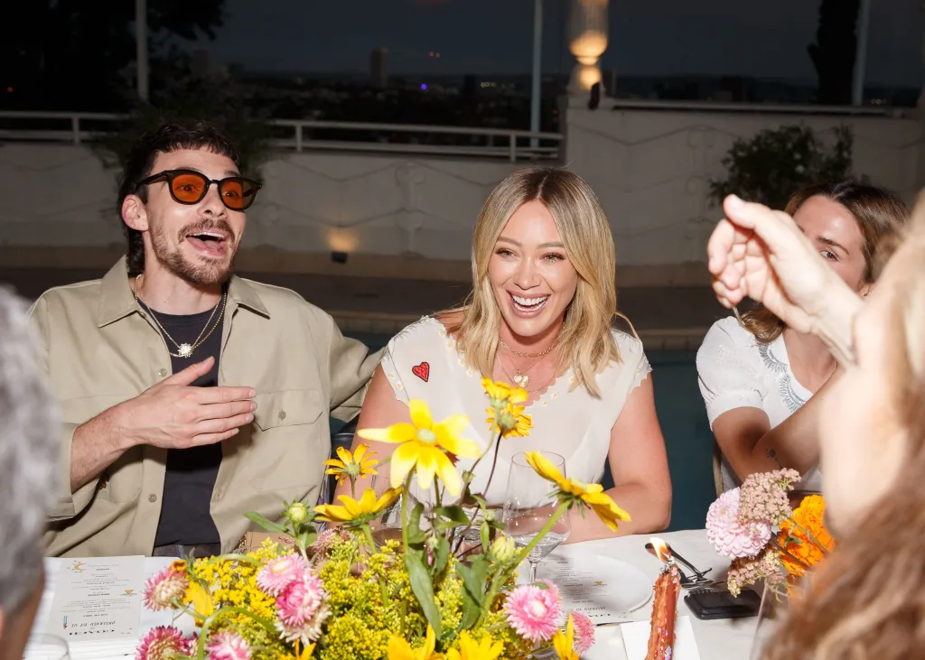 Matthew Koma, wearing sunglasses, and Hilary Duff, smiling, at a dinner.