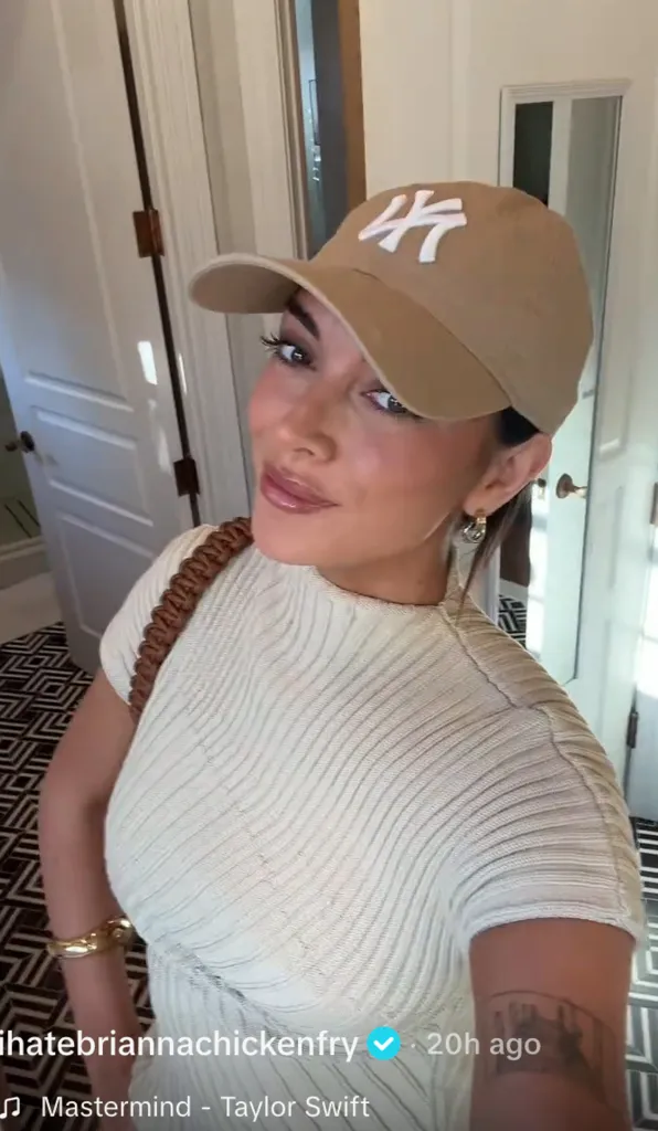 Brianna Chickenfry wearing a beige New York Yankees baseball cap and a cream-colored ribbed dress, with a brown braided strap over her shoulder, smiling at the camera.