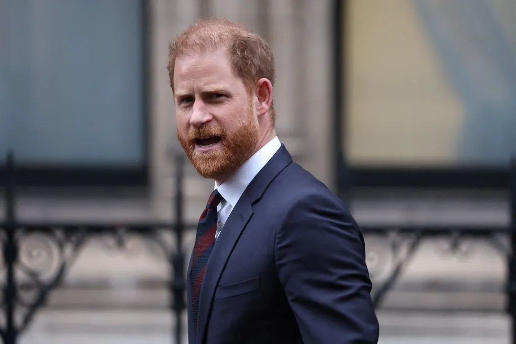 Prince Harry in a blue suit and tred and blue striped tie and white shirt, departing a London court.