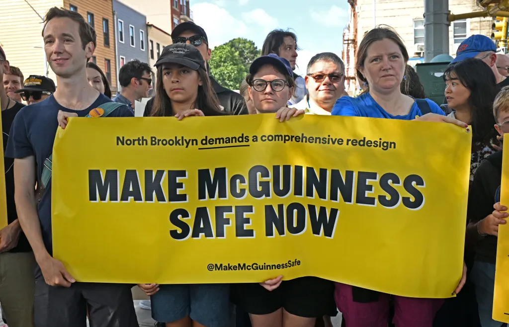 Bike safety supporters hold up a banner at the corner of McGuinness Boulevard and Calyer Street.