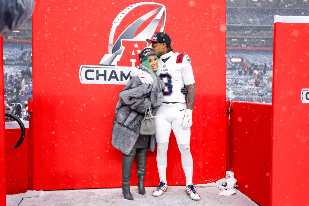 Cardi B and Stefon Diggs pose for a portrait in front of a red AFC Championship banner.