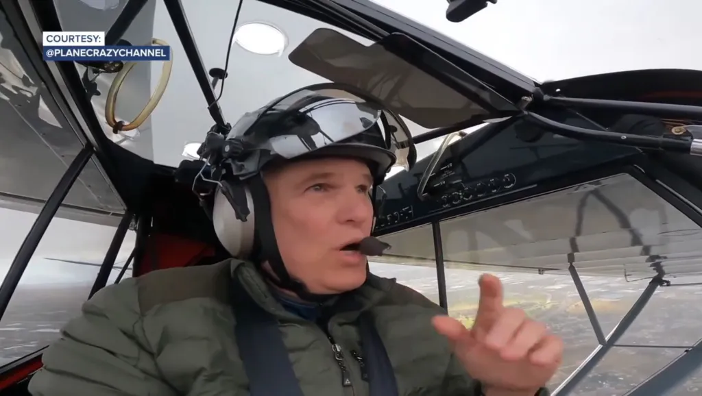 Roland Steadham, wearing a helmet and headset, piloting a small aircraft.