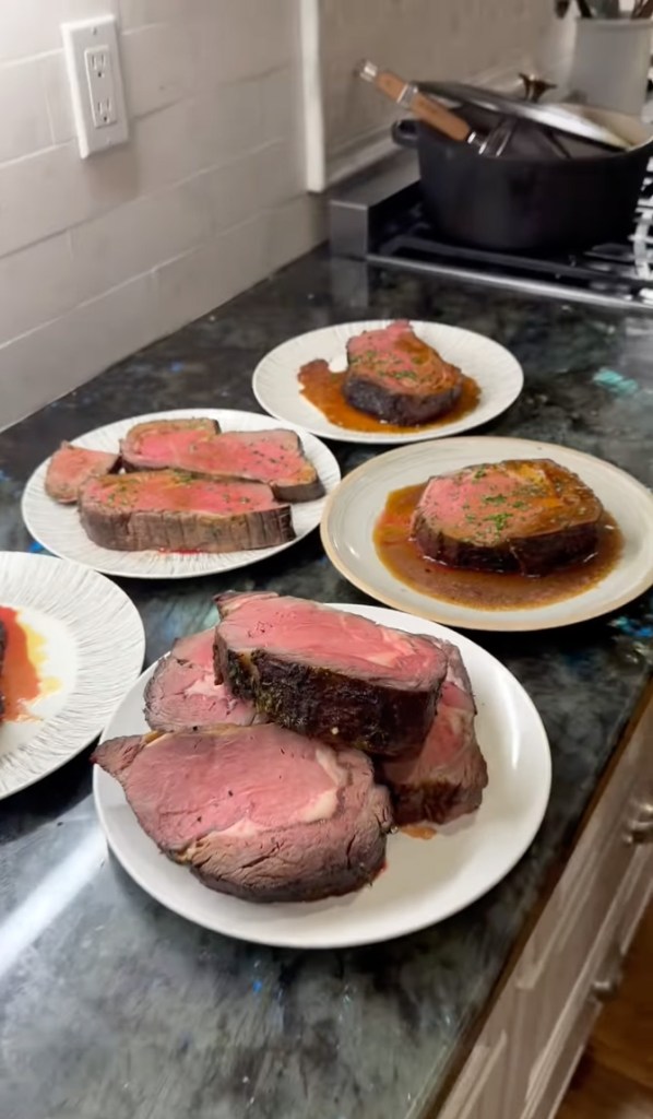 Plates of cooked prime rib on a kitchen counter.