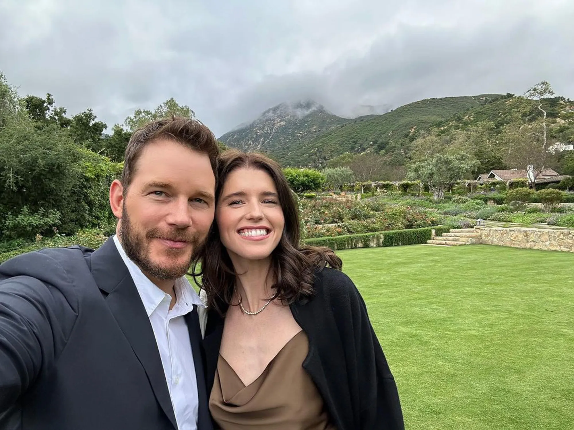 Chris Pratt and Katherine Schwarzenegger smile for a selfie outdoors.