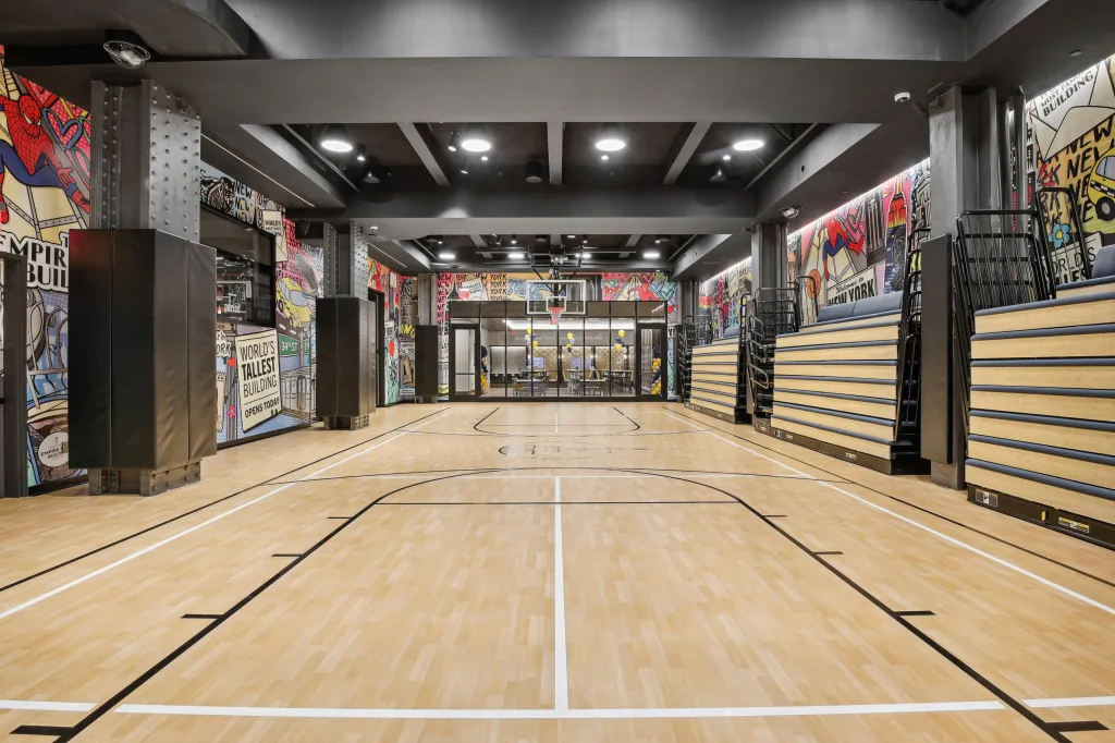 Empire State Building basketball court with bleachers and comic book-themed murals.