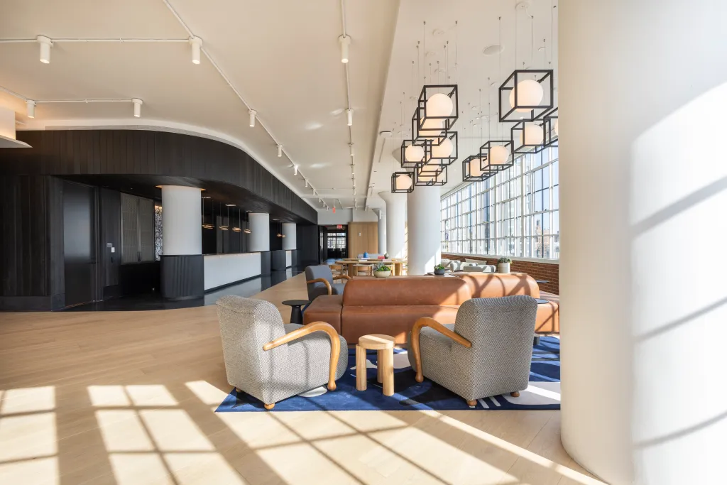 Seating area with a brown couch, two armchairs on a blue patterned rug, and large windows in the Starrett Lehigh Building and Level Ten.