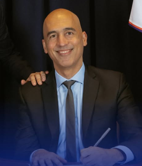 Ramzi Kassem smiling and signing a document.