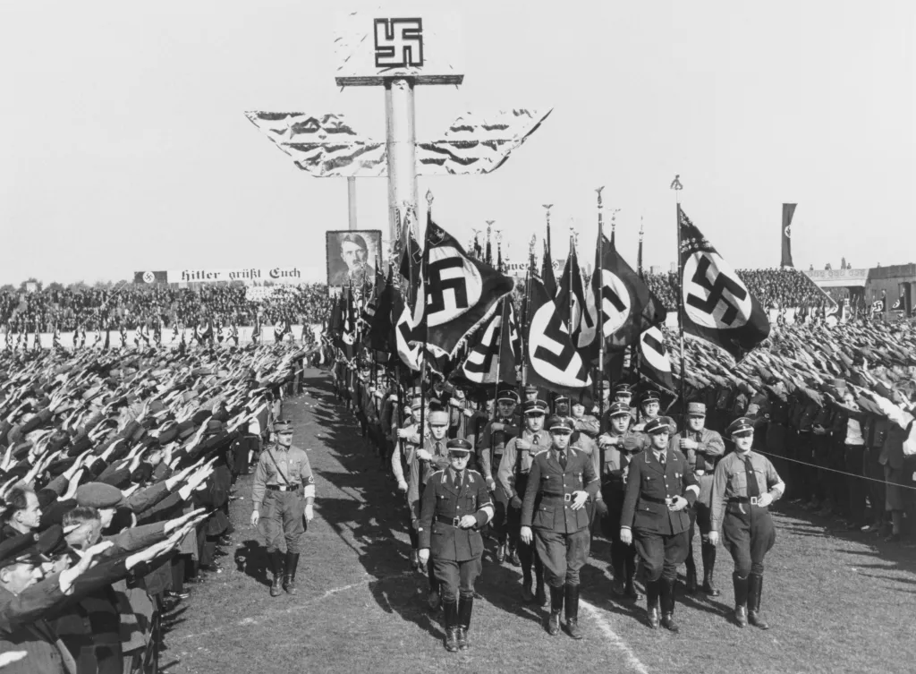 Crowds giving the Nazi salute as soldiers march past in Nuremberg, 1937.