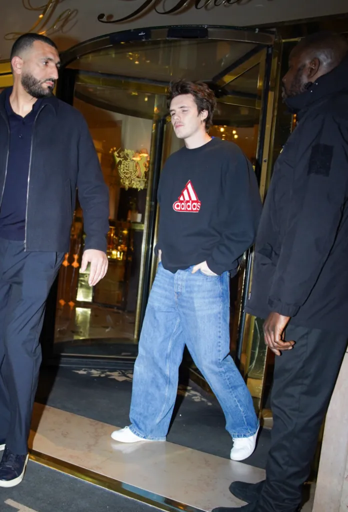 Cruz Beckham wearing a black Adidas sweatshirt, light blue baggy jeans, and white sneakers, arriving at Restaurant Kaspia in Paris.