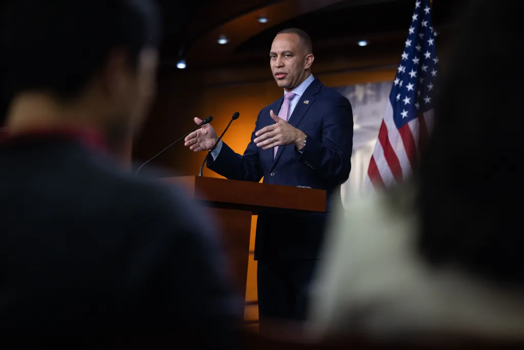 House Minority Leader Hakeem Jeffries speaking at a press conference with an American flag behind him.