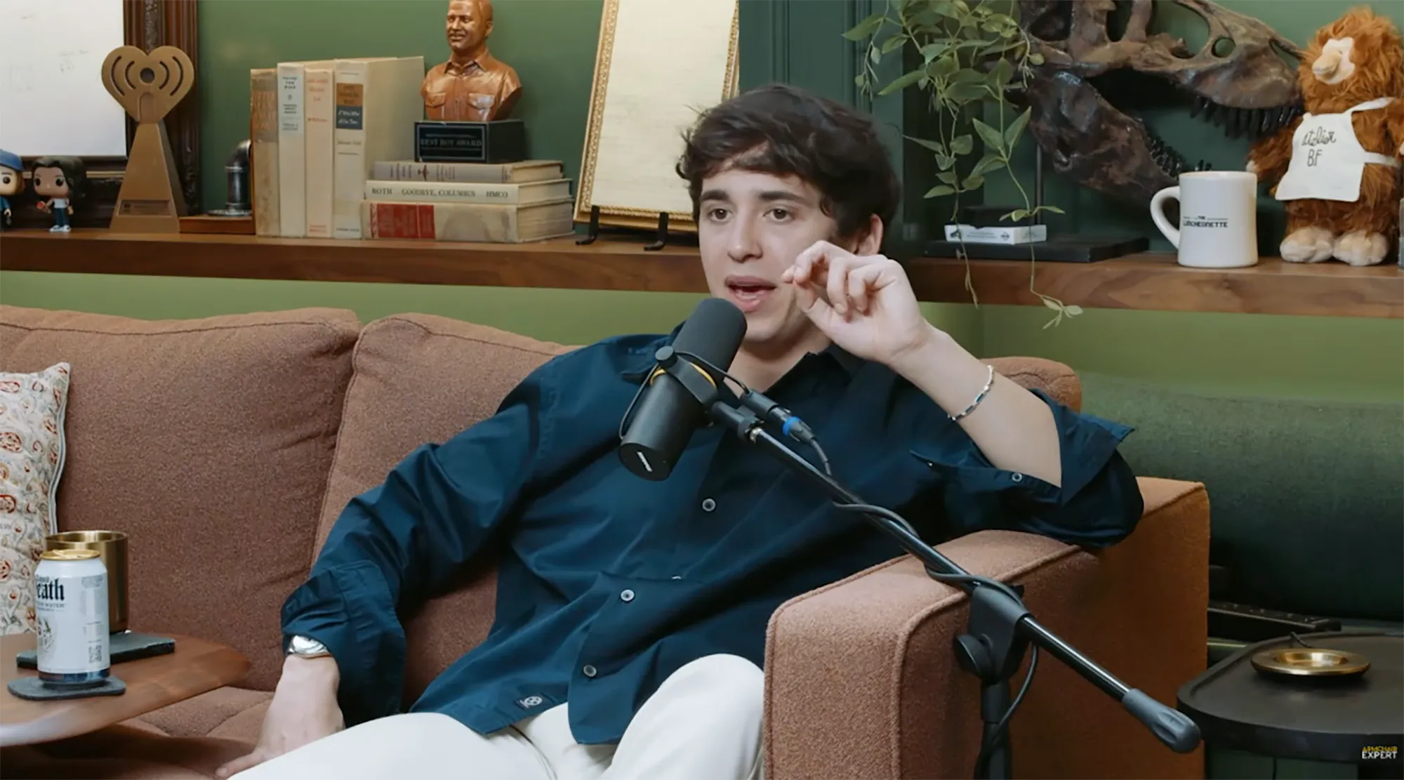 Marcello Hernández sitting on a couch next to a microphone.