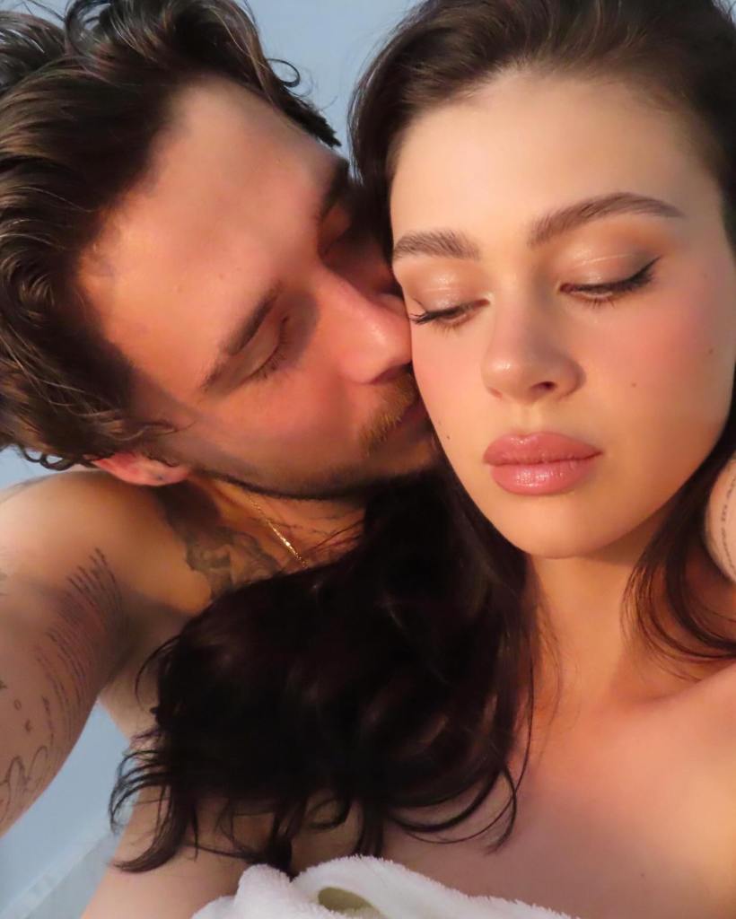 Brooklyn Beckham kissing Nicola Peltz Beckham on the cheek.