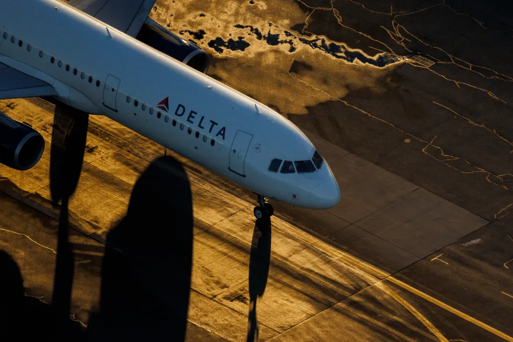 Aerial photo of a Delta aircraft taxiing on the runway during a winter sunset.