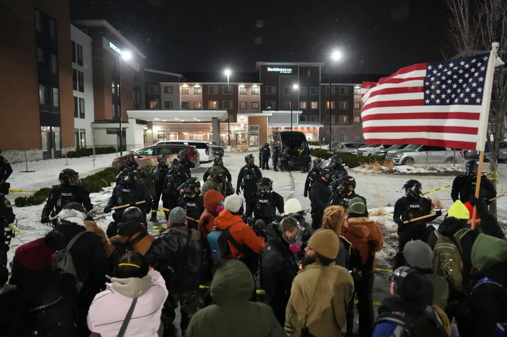 Demonstrators stand against law enforcement officers during a protest outside SpringHill Suites and Residence Inn by Marriott hotels on Monday, Jan. 26, 2026