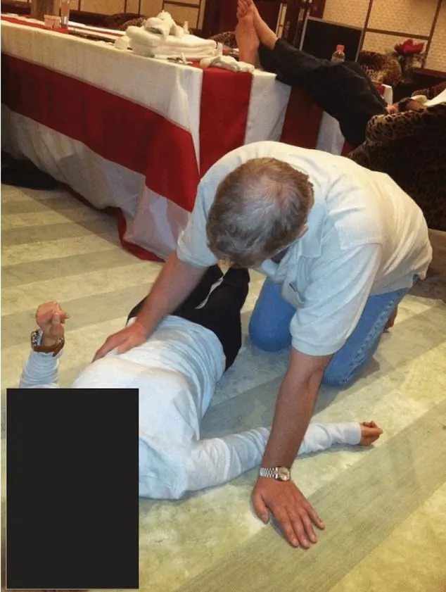 Man in a white polo shirt and jeans kneeling over a person lying on the floor.