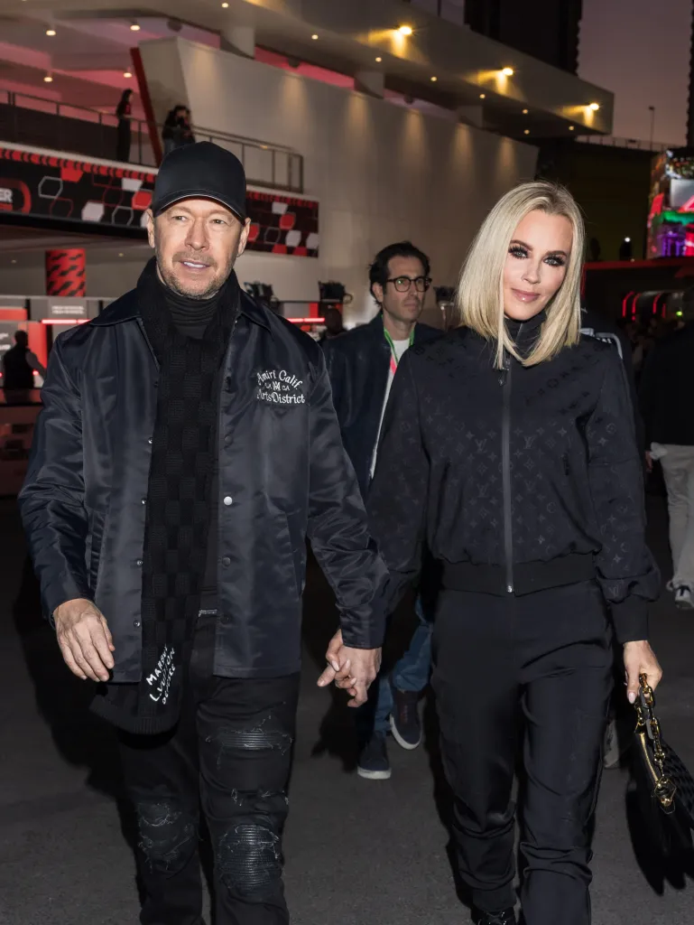 Donnie Wahlberg and Jenny McCarthy holding hands while attending the F1 Grand Prix of Las Vegas.