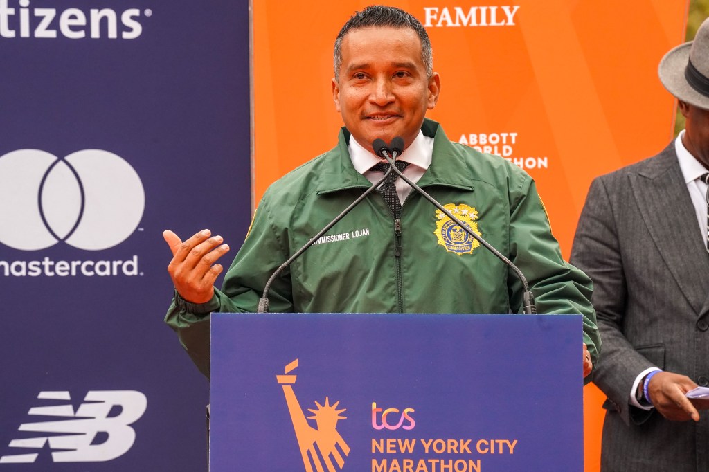 Javier Lojan, NYC Department of Sanitation Commissioner, speaking at a podium with marathon sponsor logos.