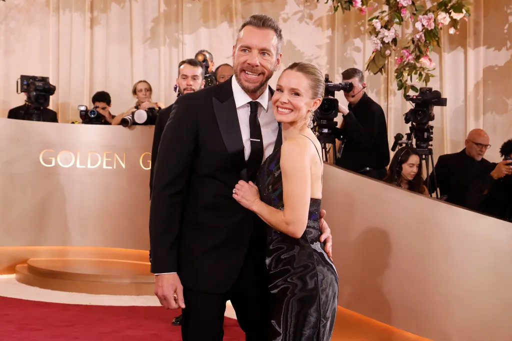 Dax Shepard in a black tuxedo and Kristen Bell in a black dress posing together at the 83rd Annual Golden Globe Awards.