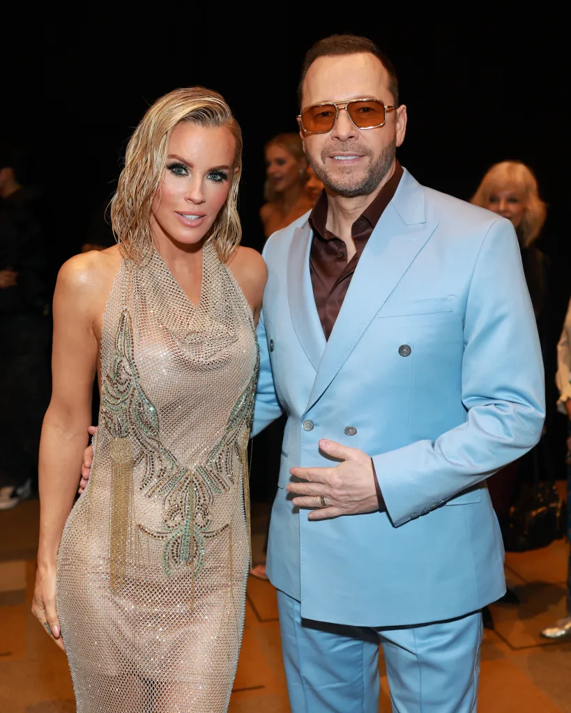 Jenny McCarthy in a sheer embellished gown and Donnie Wahlberg in a light blue suit and orange sunglasses at the 2025 iHeartRadio Music Awards.