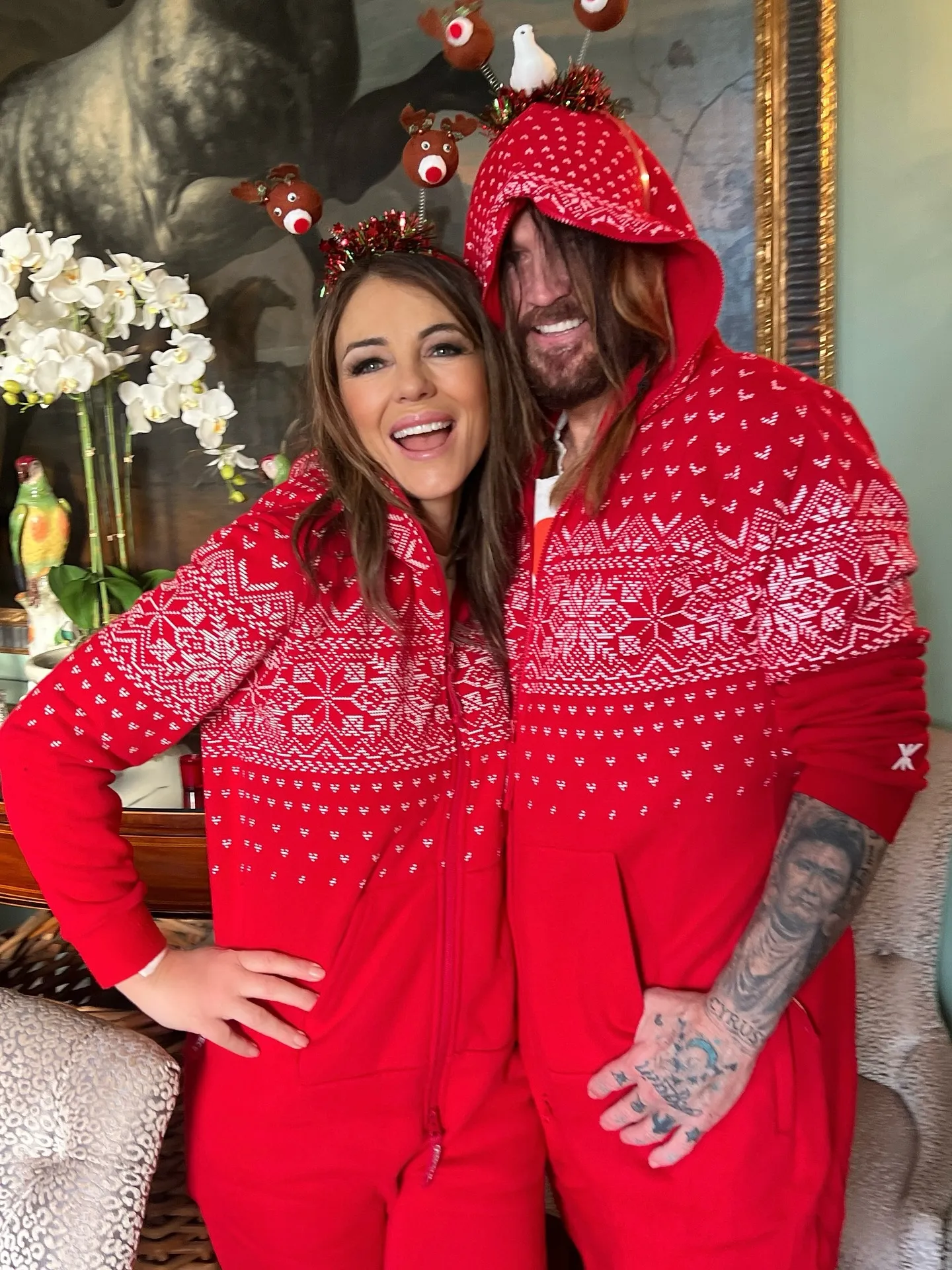 Elizabeth Hurley and Billy Ray Cyrus in matching red Christmas pajamas.