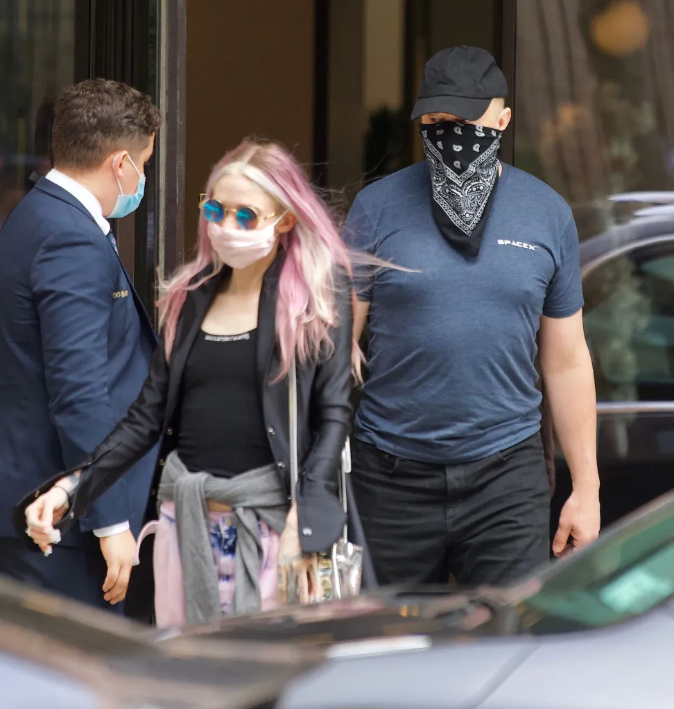 Elon Musk and Grimes exiting a New York City hotel with a security guard.