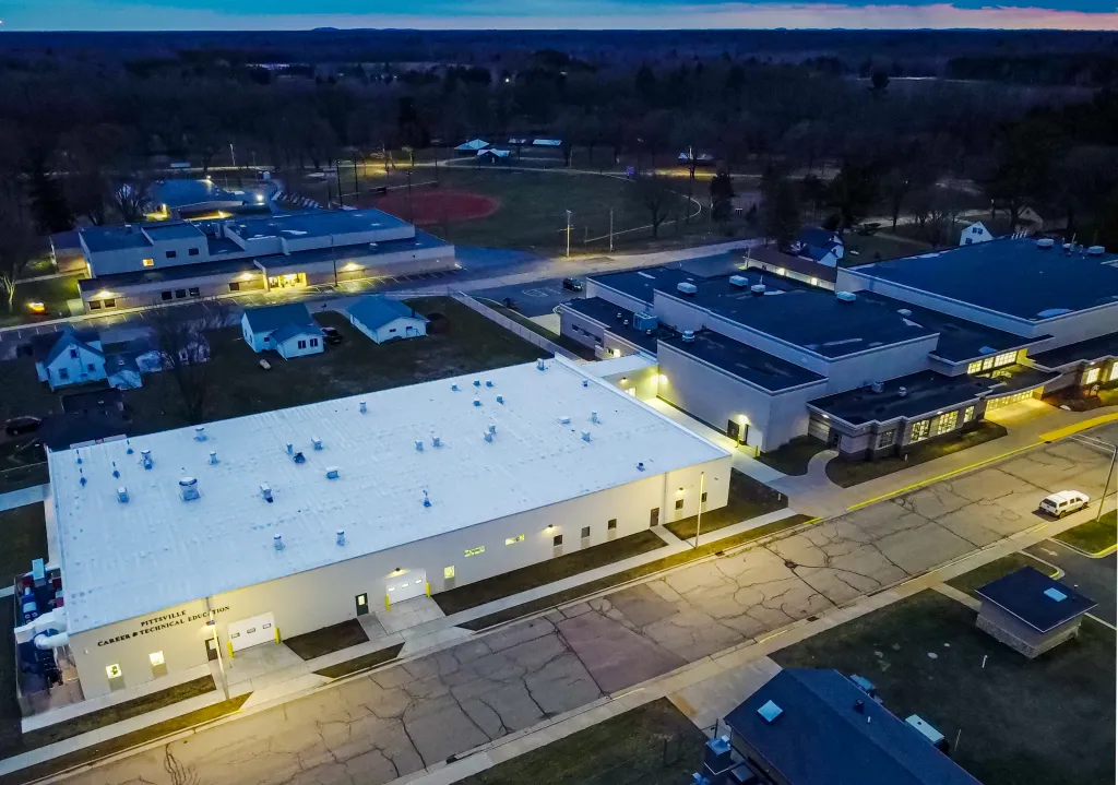Aerial view of Pittsville Career & Technical Education building and surrounding school campus at dusk.