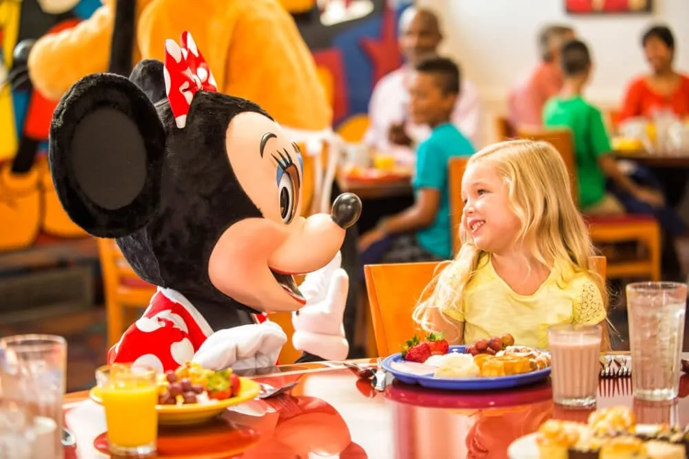 Minnie Mouse interacts with a smiling young girl at a character meal.