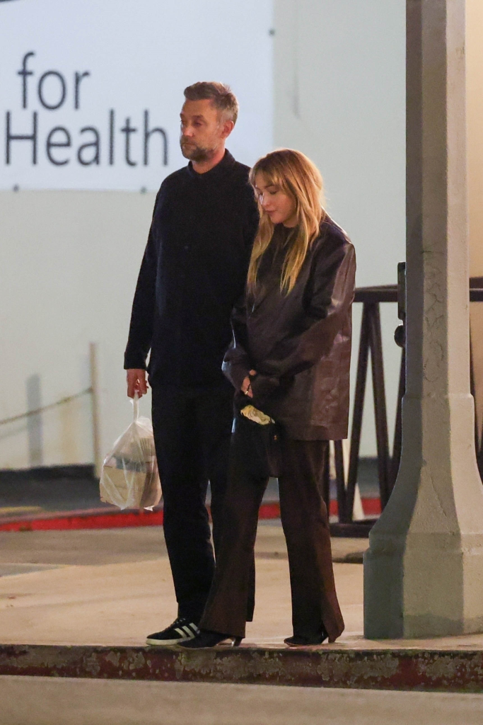 Jennifer Lawrence wearing a brown leather coat and Cooke Maroney in black clothes walking together.