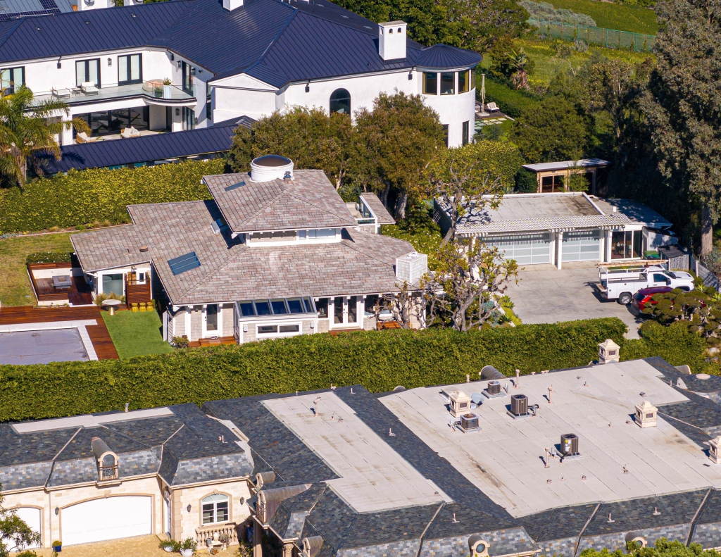 Aerial view of Kamala Harris' new home in Malibu, California, showing a large residence with a swimming pool and surrounded by lush greenery, with other houses nearby.