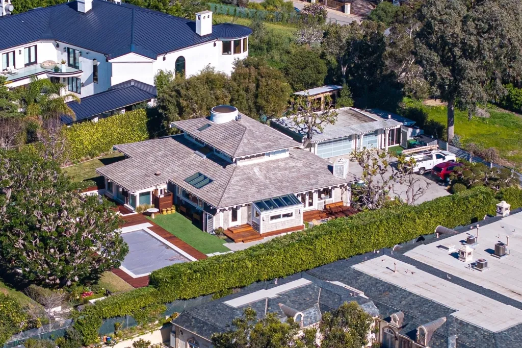 Aerial view of Kamala Harris' new home in Malibu, featuring a house with a shingled roof, a swimming pool, and manicured landscaping.