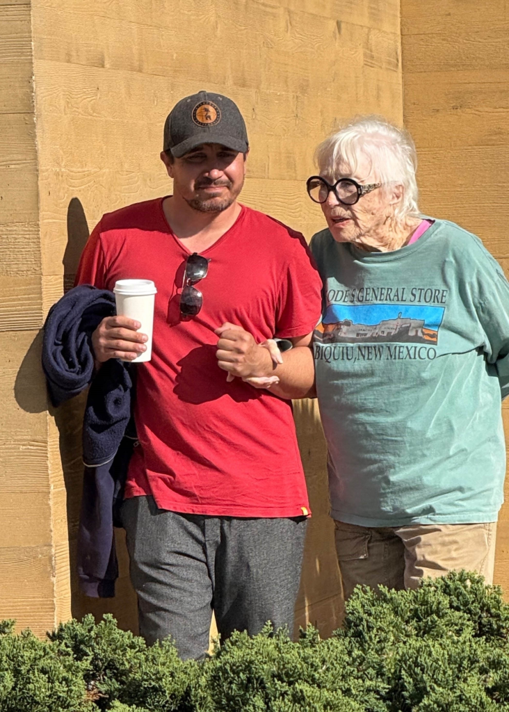 Shirley MacLaine being assisted by a companion while leaving a restaurant.