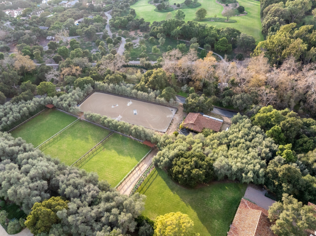 Aerial view of Kendall Jenner's Montecito estate, featuring equestrian facilities with stables, training grounds for show jumping, and surrounding green landscapes.