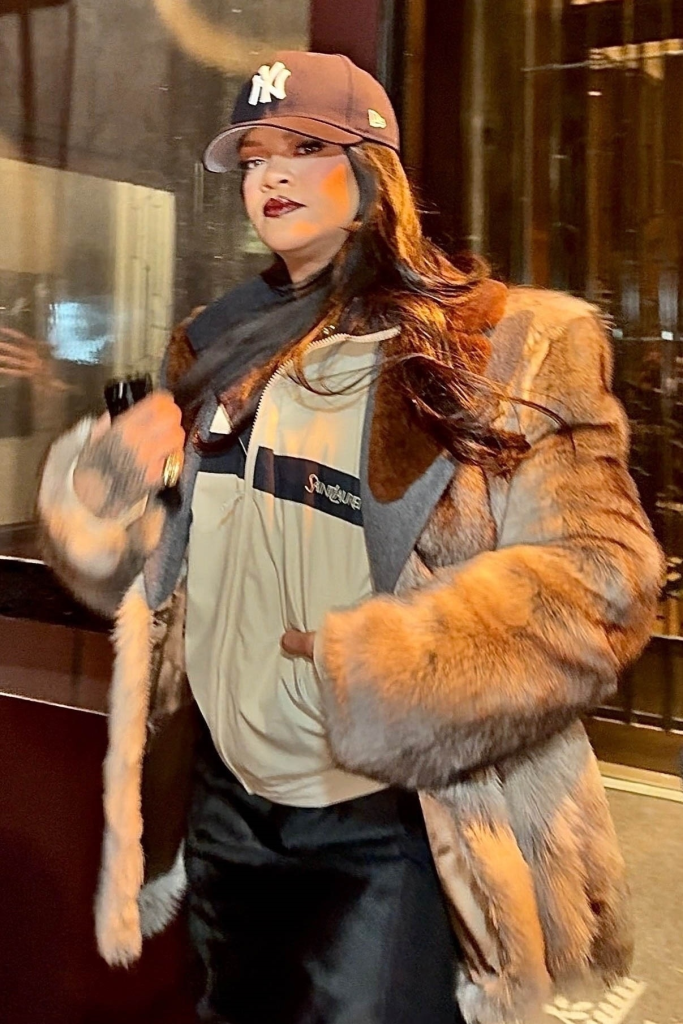 Rihanna leaving a hotel, wearing a baseball cap, an oversized jacket, and a fur coat.