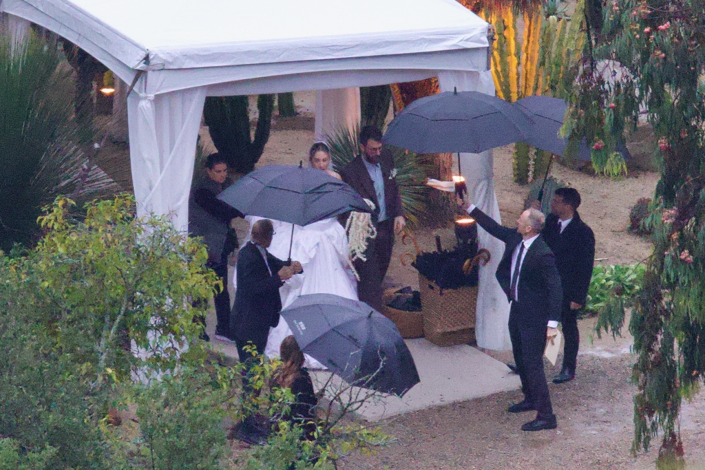 Este Haim and Jonathan Levin on their wedding day with people holding umbrellas over them.