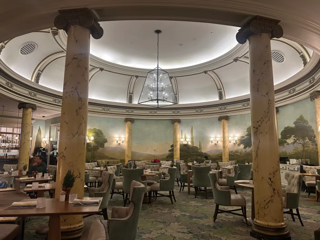 Dining room in the Fairmont Hotel with large decorative columns and a mural of a landscape along the walls.