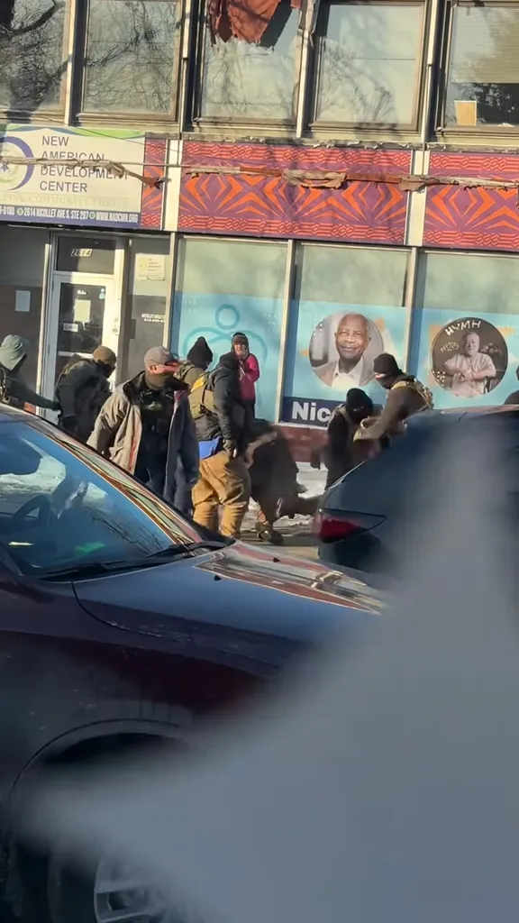 A group of law enforcement agents detaining a man in front of the New American Development Center.