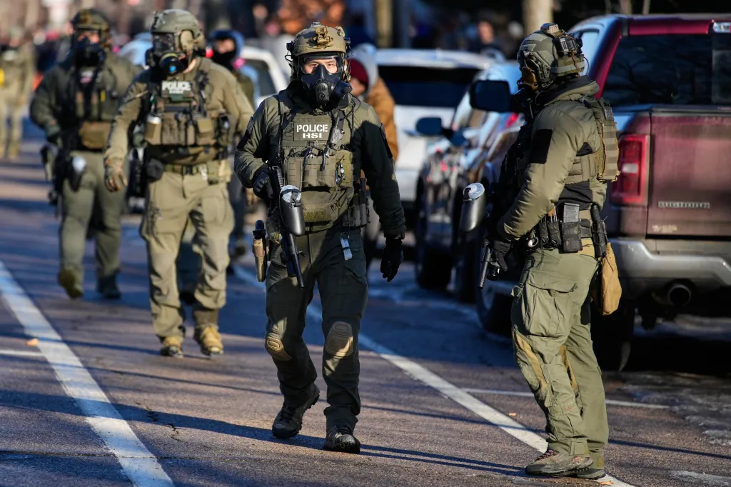 Federal immigration officers walk on a street in Minneapolis.