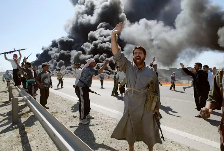 Men carrying guns and celebrating, with huge black clouds behind them.