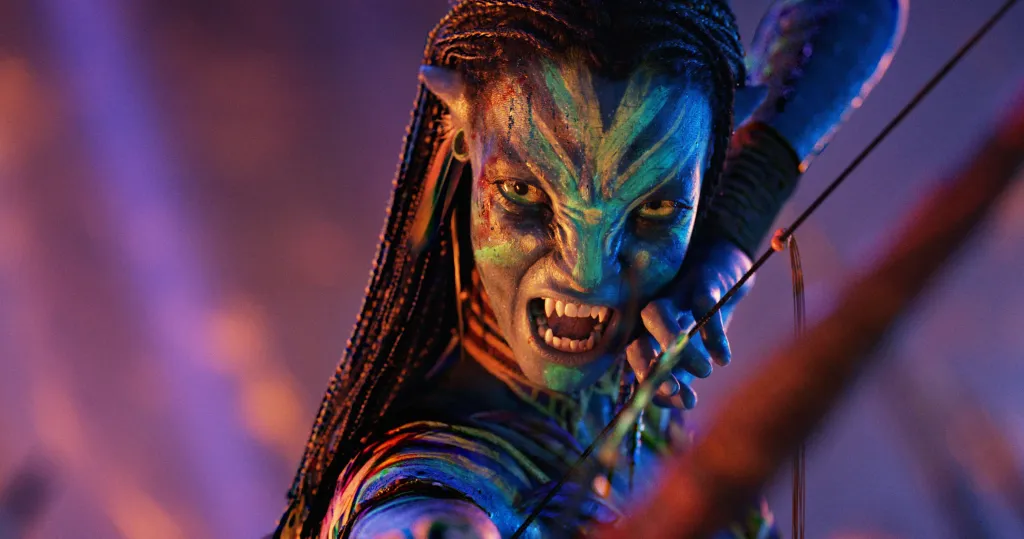 Neytiri from Avatar grimacing with bared fangs while drawing a bow.