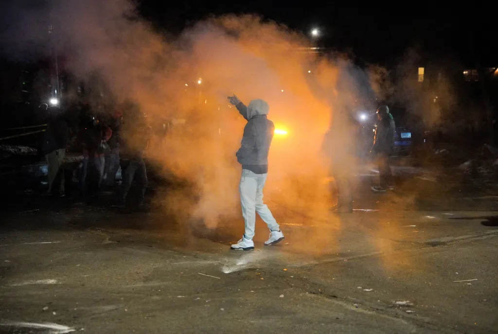 A protester gestures to federal agents after fire munitions and pepper balls were deployed on a crowd in Minneapolis, Minnesota, on Jan. 14, 2026.
