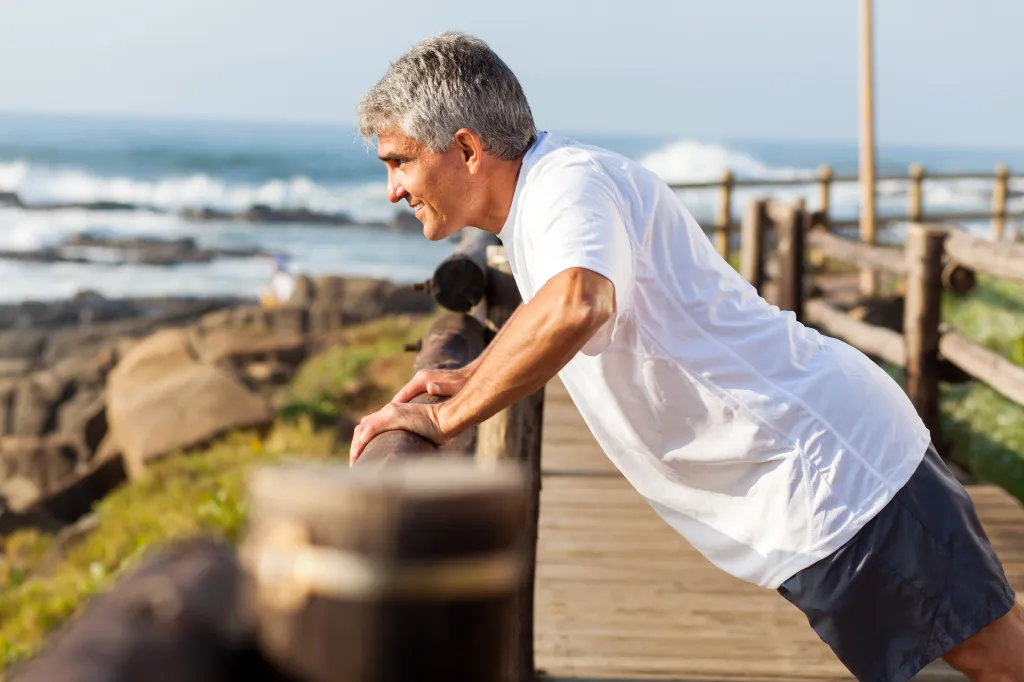 Fit senior man doing push-ups at the beach.