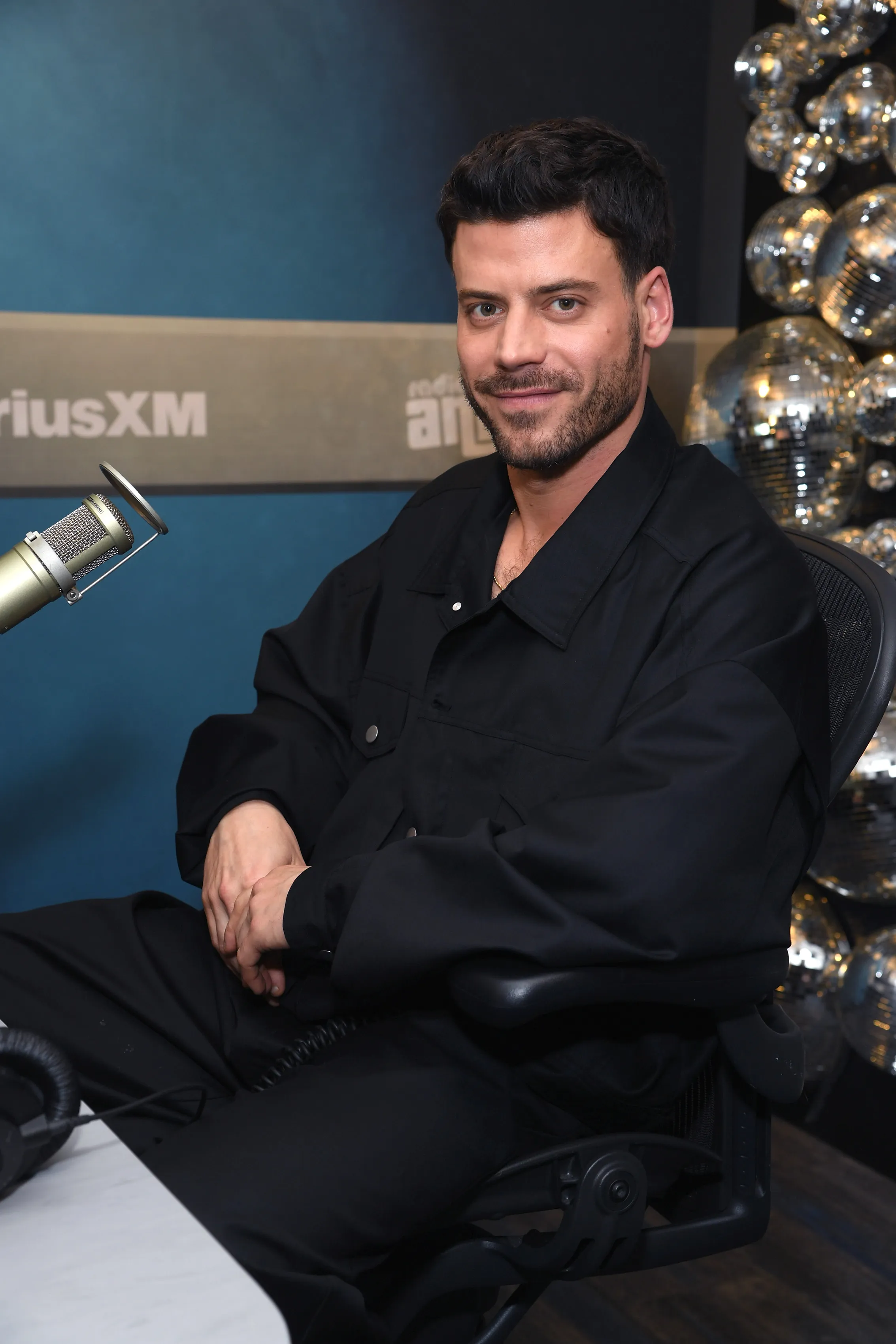Francois Arnaud posing in front of a microphone at SiriusXM Studios.