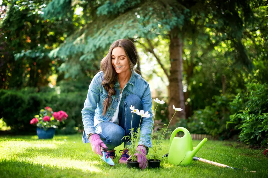 Happy young woman planting flowers in the garden.