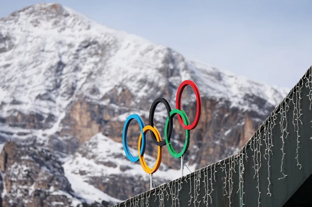 Olympic rings against a snowy mountain backdrop.