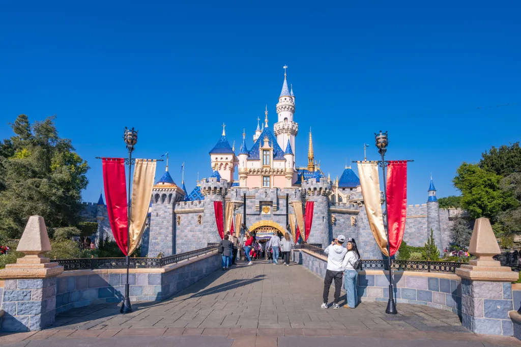 Sleeping Beauty Castle at Disneyland, with visitors on the bridge in the foreground.