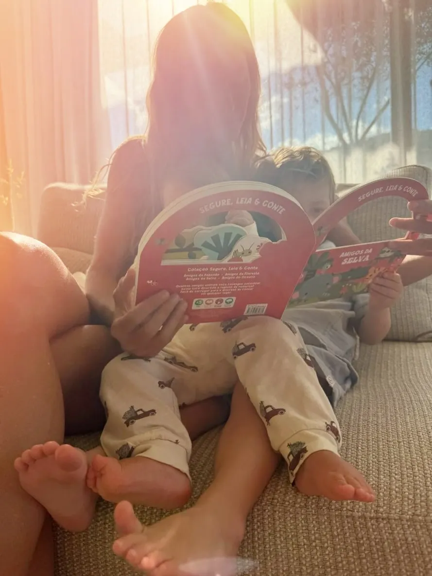 Two people sitting on a couch reading books, with bright sunlight shining on them.