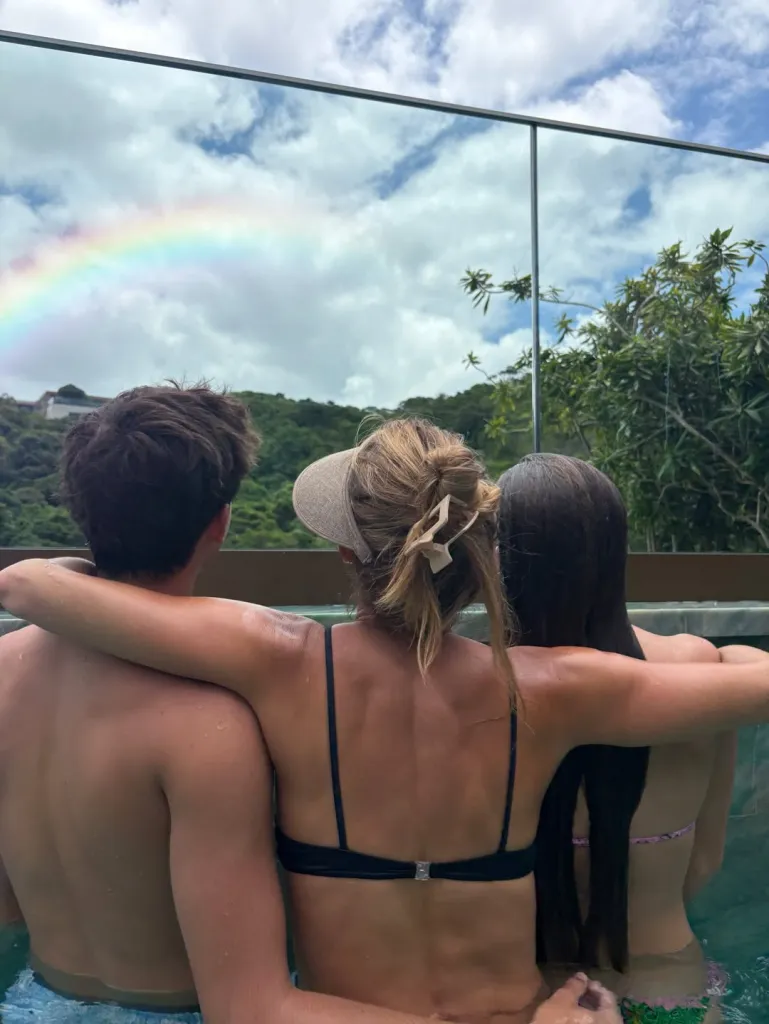 Gisele Bündchen, with her two children, looking at a rainbow from an infinity pool.